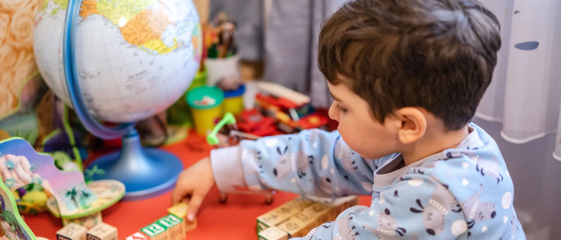 Niño jugando con bloques de letras junto a un globo terráqueo