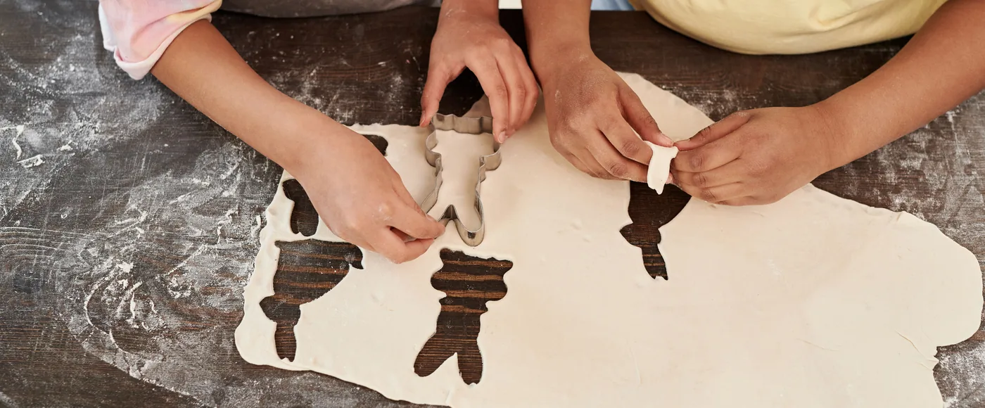 Manos cortando formas en masa de galletas
