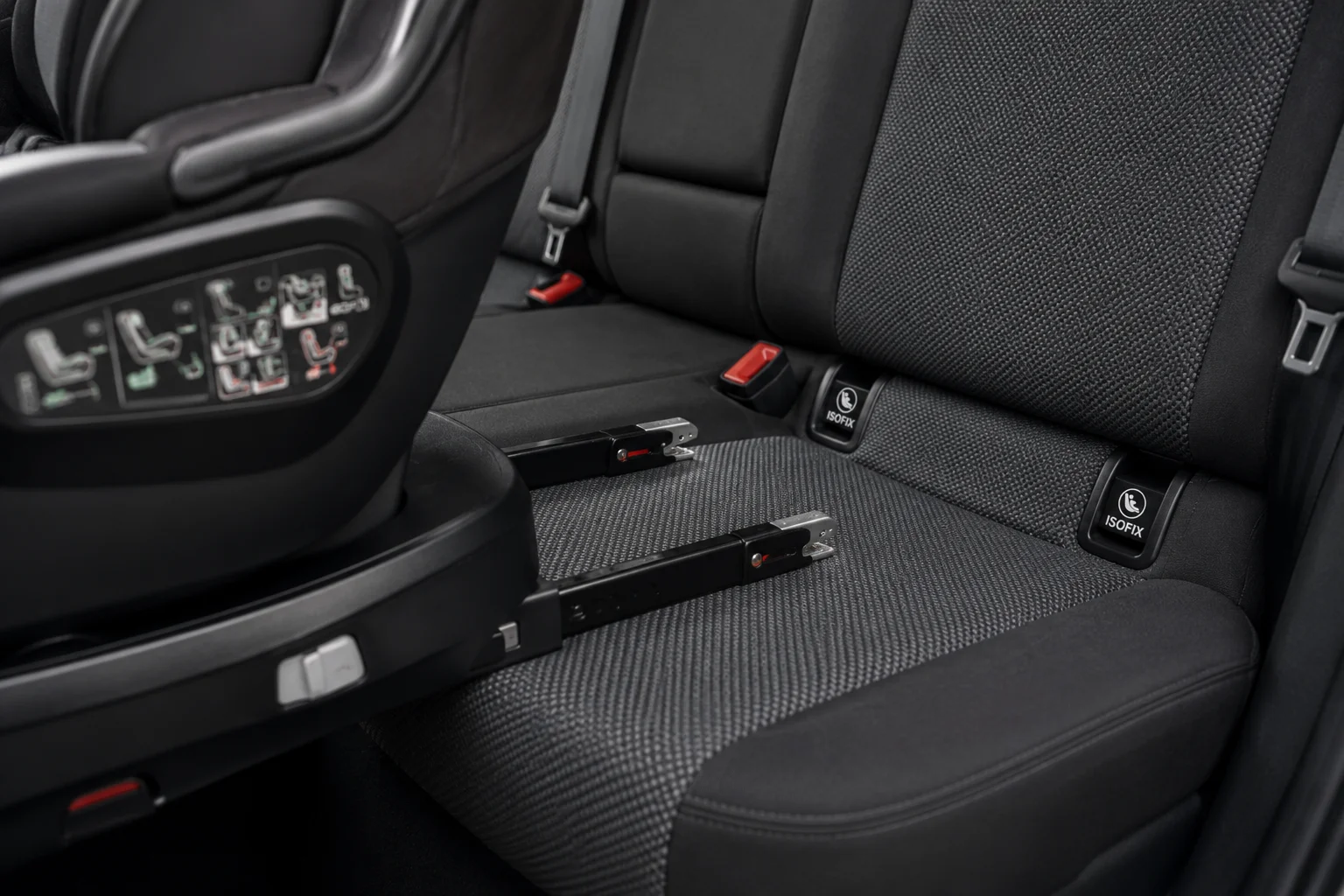 Conectores Isofix desplegados en la base de una silla de coche, junto a los anclajes del asiento trasero