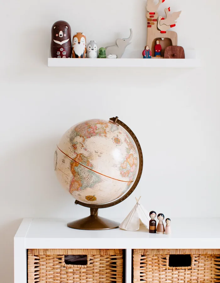 Estantería infantil ordenada con cestas de mimbre y un globo terráqueo