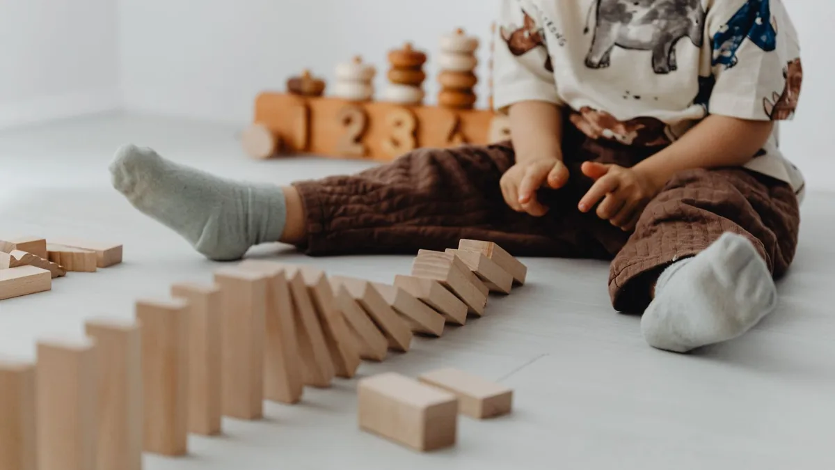 Niño pequeño explorando por iniciativa propia con bloques de madera Montessori en un ambiente luminoso y tranquilo