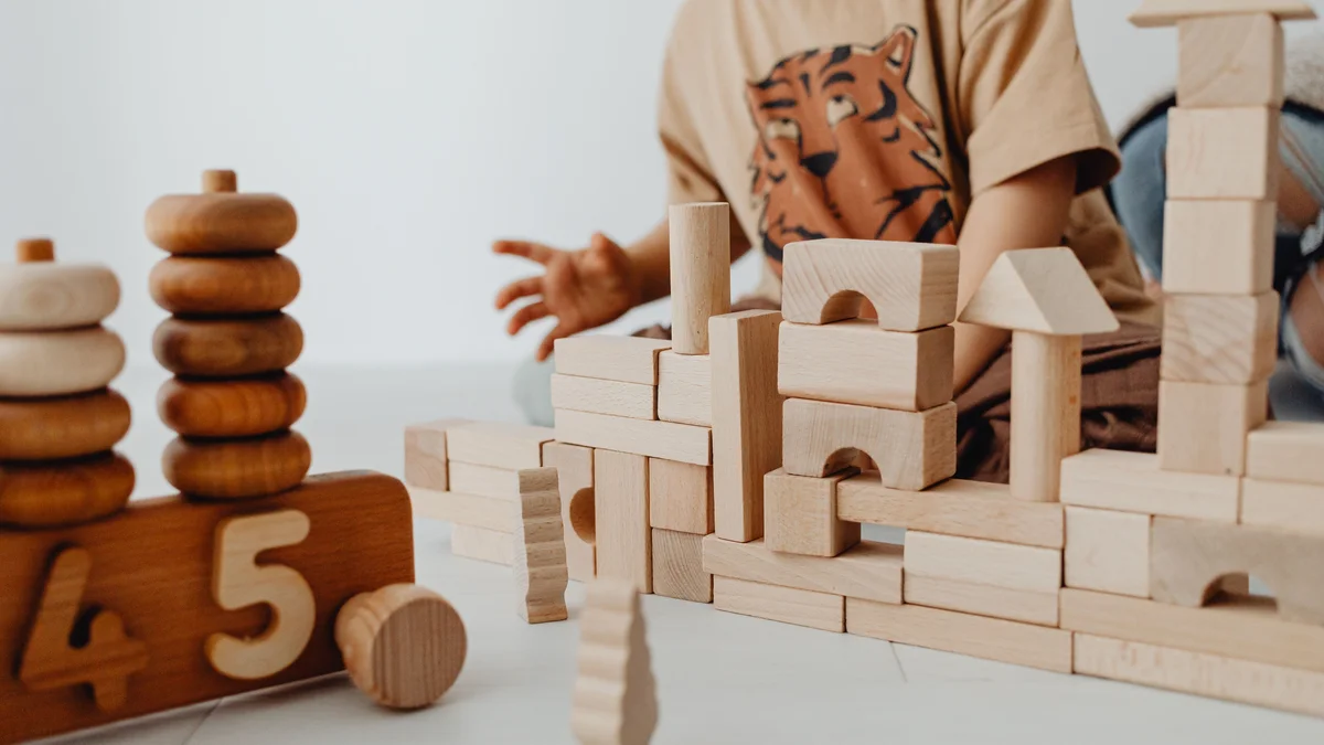 Niño jugando con bloques y construcciones de madera Montessori